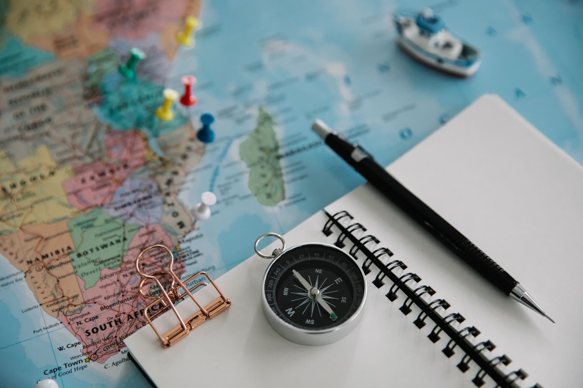 A notebook and a pinned world map laid out for trip planning